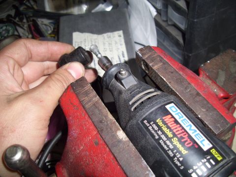 1993 Ford Probe - A Dremel MultiPro tool is used to work on a small black component secured in a red vise.