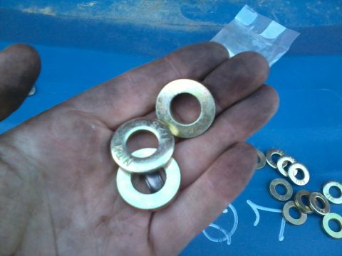 1981 Ford Bronco - A hand holds several brass washers, with more scattered on a blue surface.