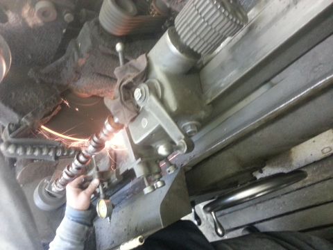 1978 Ford Bronco - A camshaft is being machined on a lathe, with sparks indicating grinding activity.