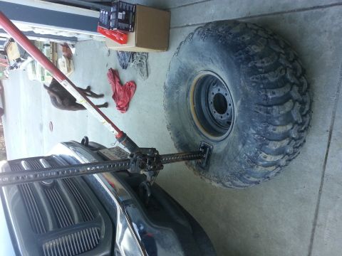 1978 Ford Bronco - A hi-lift jack is used to lift a large off-road tire on the fender of a truck.