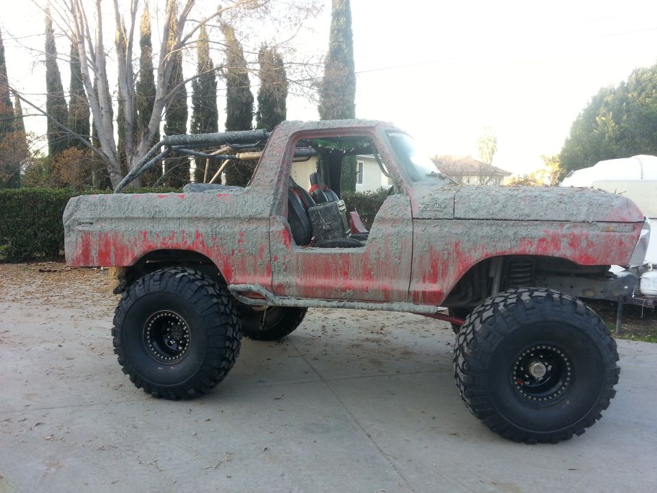 Mud-covered 1978 Ford Bronco with large off-road tires and roll cage