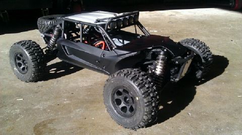 1996 Ford Bronco - This black off-road buggy features a prominent roll cage, large off-road tires, and a spare tire mounted at the rear.