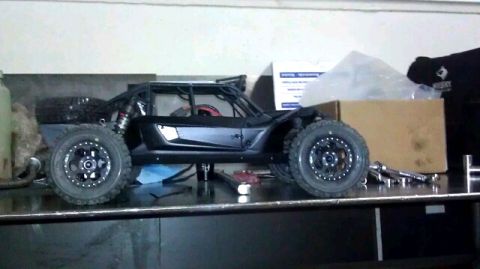 1996 Ford Bronco - A black remote control buggy with a roll cage and large off-road tires is displayed on a workbench.