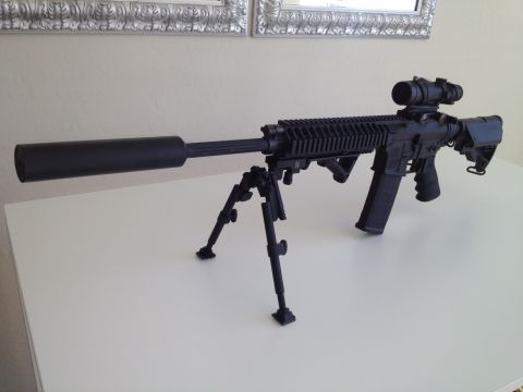 2013 Ford Mustang - A rifle equipped with a bipod, scope, and silencer is displayed on a white surface.