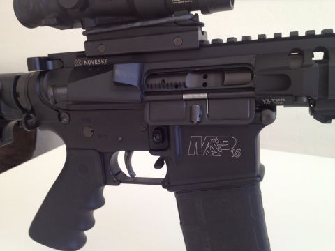 2013 Ford Mustang - Close-up view of an AR-15 style rifle's receiver, showing manufacturer markings and accessories.
