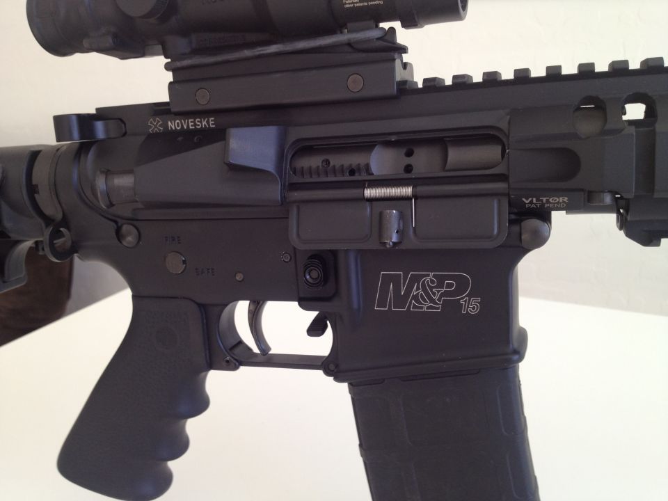 Black AR-15 rifle receiver with M&P 15 markings and a scope mounted on top