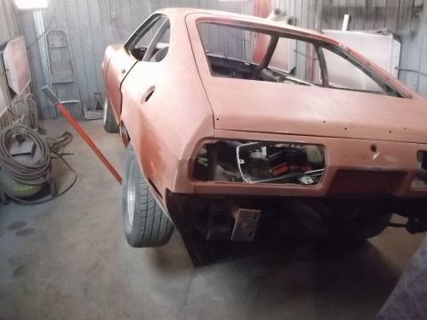 1978 Ford Mustang II - A 1978 Ford Mustang II in primer is shown from the rear in a workshop, missing its taillights and undergoing restoration.