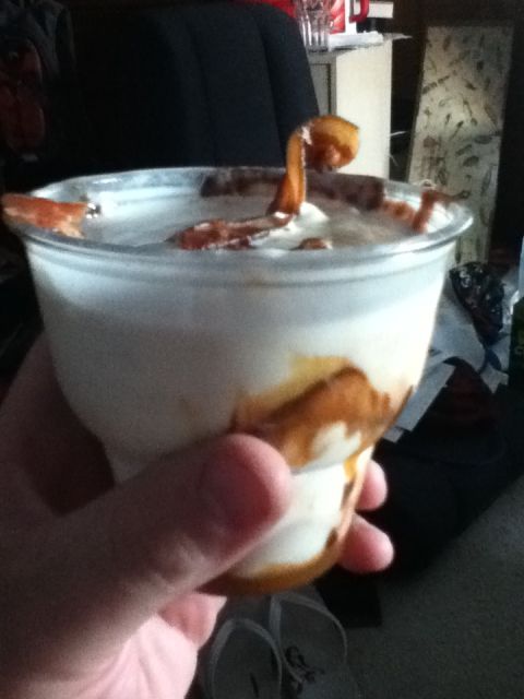 2006 Ford E350 - A hand holds a dessert cup filled with ice cream and caramel swirls, with a piece of food emerging from the top.