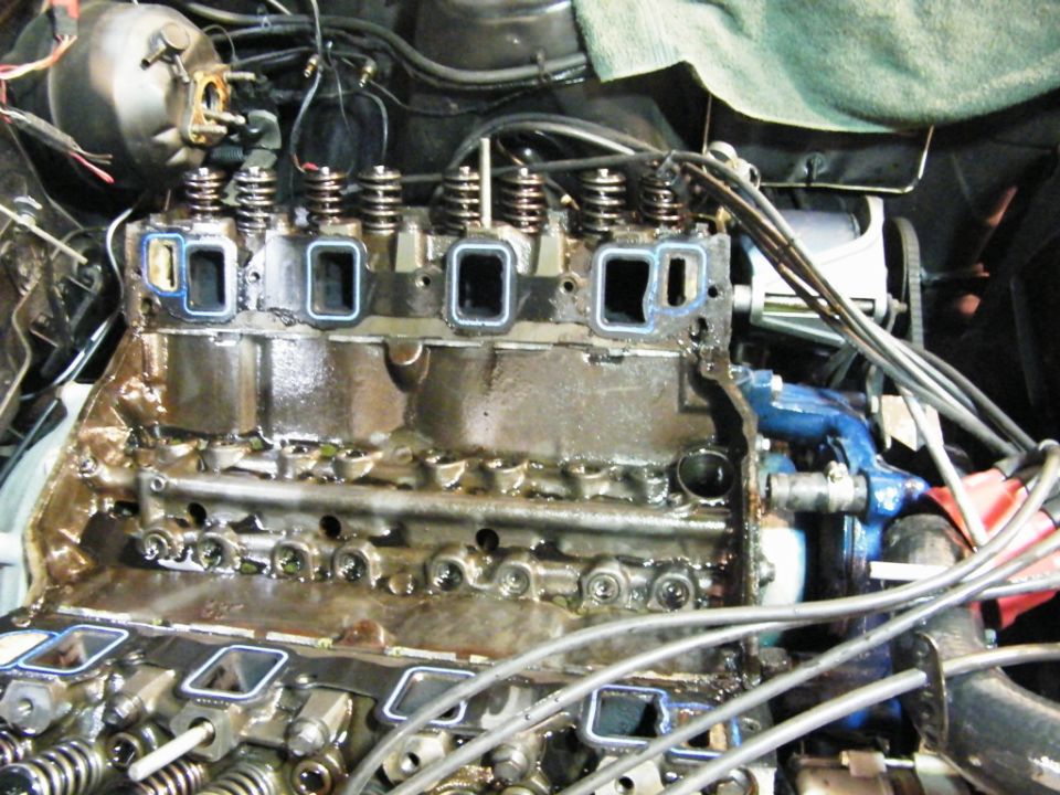 Close-up of a V8 engine block with the intake manifold off, showing the cylinder heads and valve train components