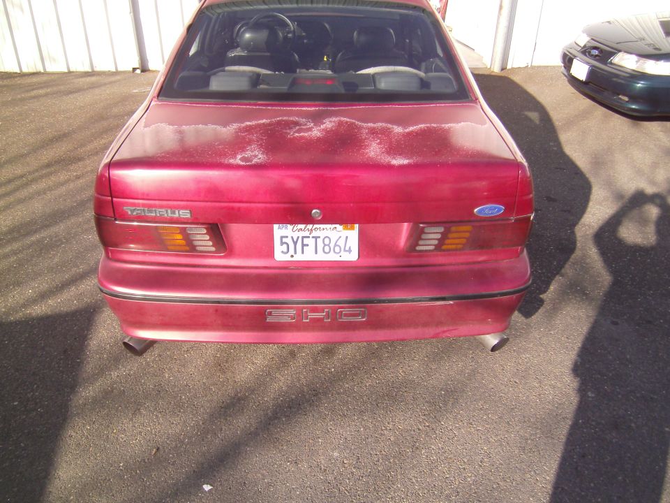 Red 1991 Ford Taurus SHO rear view with California license plate 5YFT864. Another car is visible to the right