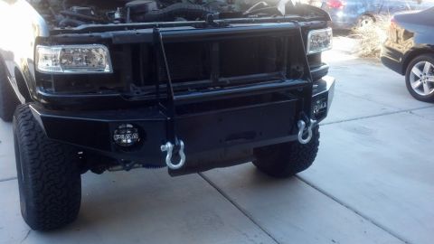 1995 Ford Bronco - This truck features a heavy-duty bumper with tow hooks and auxiliary lighting, with its hood open.