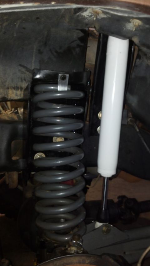 1992 Ford Bronco - Close-up view of a gray coil spring and a white shock absorber, part of a vehicle's suspension system.