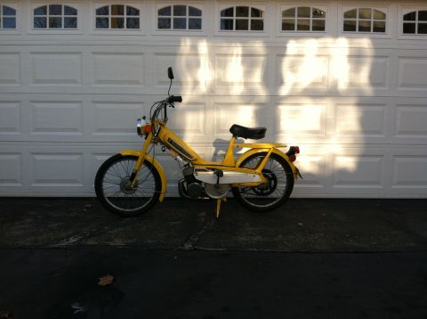 1981 Garelli Rally Sport - A yellow moped is parked in front of a white garage door with sunlight casting shadows.