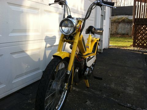 1981 Garelli Rally Sport - A yellow moped is viewed from the front, parked on an asphalt driveway next to a white garage door.