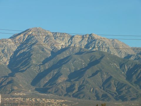 2003 Ford Crown Victoria - Telephoto view of a mountain summit with bare rocky ridges and forested lower slopes behind power cables