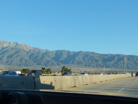 2003 Ford Crown Victoria - Cars on a multi-lane freeway separated by a concrete median wall, mountains and transmission towers beyond