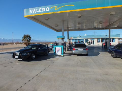 2003 Ford Crown Victoria - Black sedan with front plate at a Valero station, a gray sedan fueling and a group by the CFN kiosk