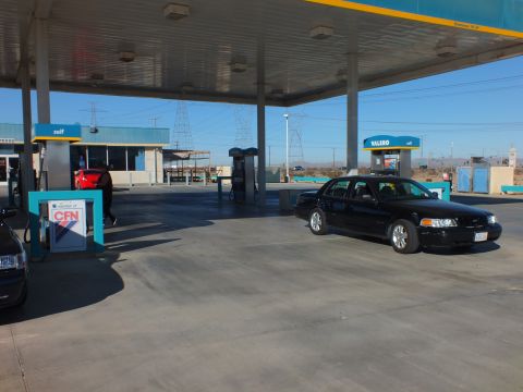 2003 Ford Crown Victoria - Single black sedan parked under a fuel canopy near a CFN card-lock kiosk with a Valero sign beyond