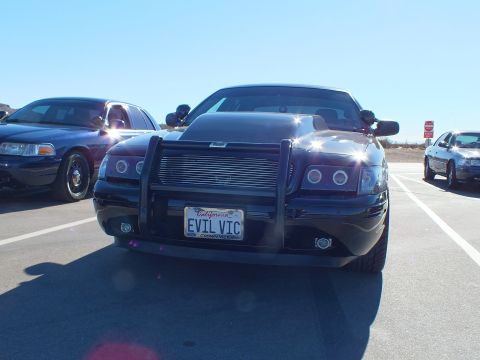 2003 Ford Crown Victoria - Modified black sedan with chrome grille and push bar bears an EVIL VIC license plate