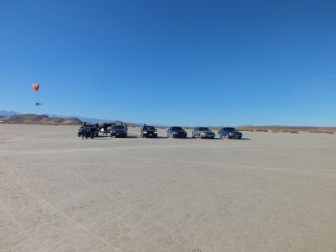 2003 Ford Crown Victoria - Line of sedans on a desert dry lake with an orange powered paraglider flying at left