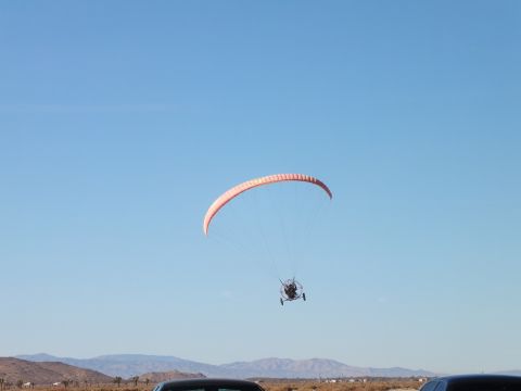 2003 Ford Crown Victoria - Powered paraglider trike hovers above a desert with mountains on the skyline