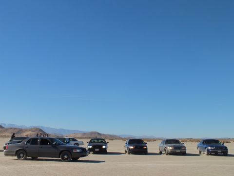 2003 Ford Crown Victoria - Silver sedan at left fronts a lineup of cars across a desert dry lake