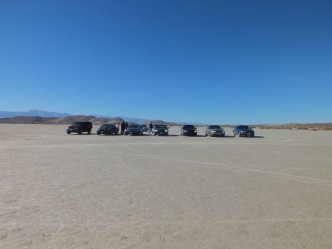 2003 Ford Crown Victoria - Sedans clustered far across an expansive desert dry lake with mountains beyond