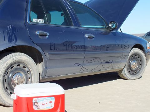 2003 Ford Crown Victoria - Blue Crown Victoria side scrawled EL MIRAGE POLICE, K9 Unit 243 with flame doodles; red cooler in the foreground.
