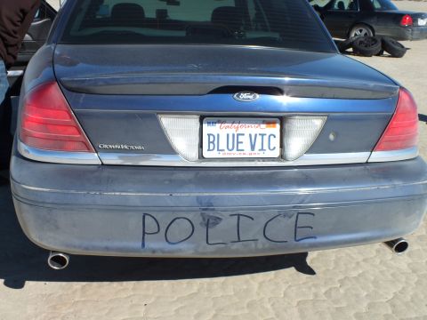 2003 Ford Crown Victoria - Crown Victoria tail showing Ford oval, BLUE VIC plate and POLICE hand-written across the dirty bumper.