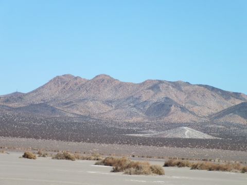 2003 Ford Crown Victoria - Brown desert mountains with scattered scrub in the foreground and pale lakebed under a clear sky.