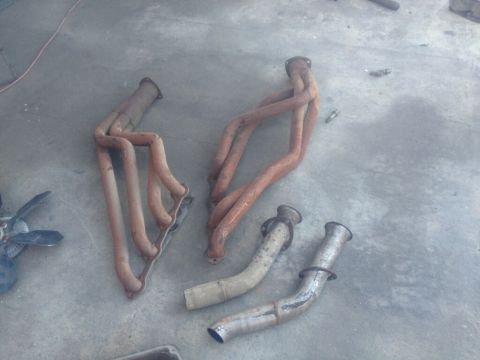1964 Ford Ranchero - A collection of exhaust components, including headers and pipes, lies on a concrete surface.
