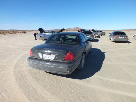 2003 Ford Crown Victoria - Rear of a gray Crown Victoria, California plate 5JBS368, in a cluster of cars on a dry lakebed