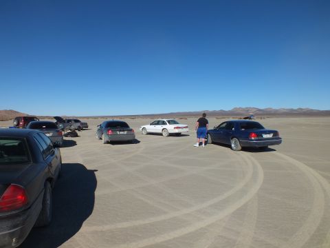 2003 Ford Crown Victoria - Several Crown Victoria sedans spread across a flat dry lakebed, one person walking between them