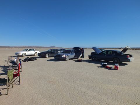 2003 Ford Crown Victoria - Cars parked with hoods open and folding chairs set up at left on an open dry lakebed