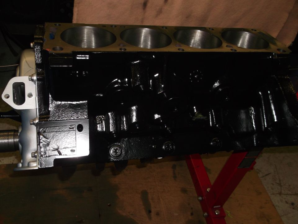 Black engine block on red stand, showing cylinders and mounting bracket
