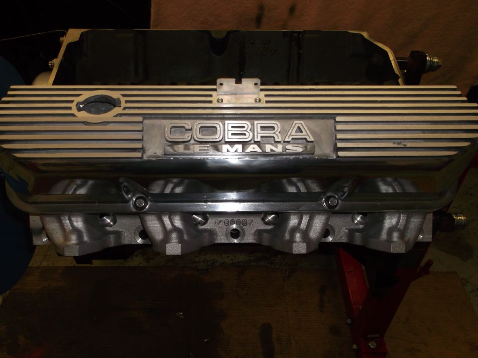Close-up of a Cobra Le Mans engine valve cover with ribbed metal and chrome accents
