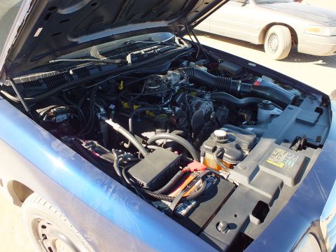 2003 Ford Crown Victoria - Detailed underhood shot of a light blue Crown Victoria engine, white sedan parked just behind.