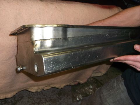 1965 Shelby Cobra - A person holds a metal oil pan, showing its construction and bolt attachments.