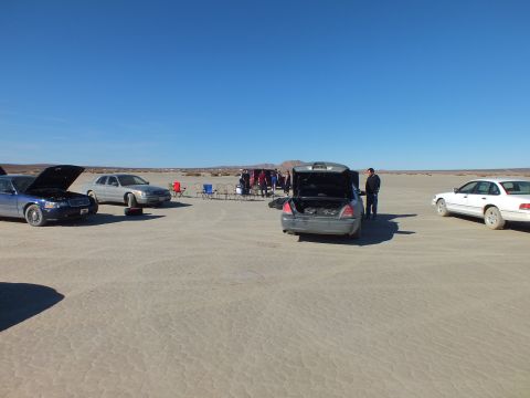 2003 Ford Crown Victoria - meet of Crown Victoria sedans spread across the playa, hoods and a trunk open, people gathered.