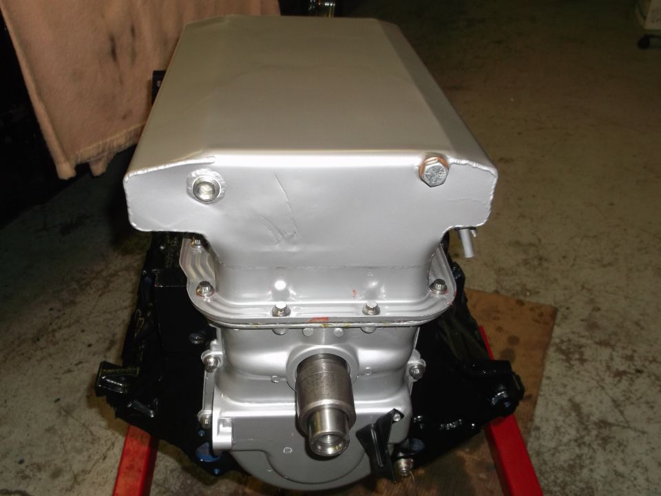 Silver engine oil pan with bolts and a shaft protruding