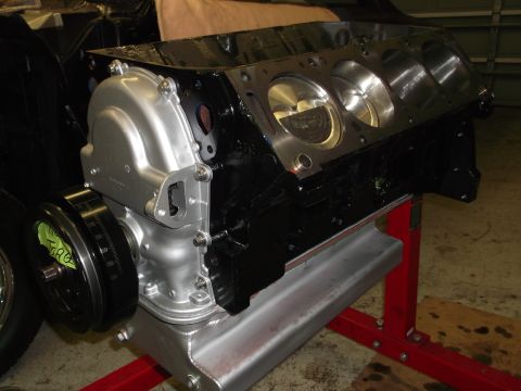 1965 Shelby Cobra - Engine block assembly with timing cover and pulley, supported by a red stand.