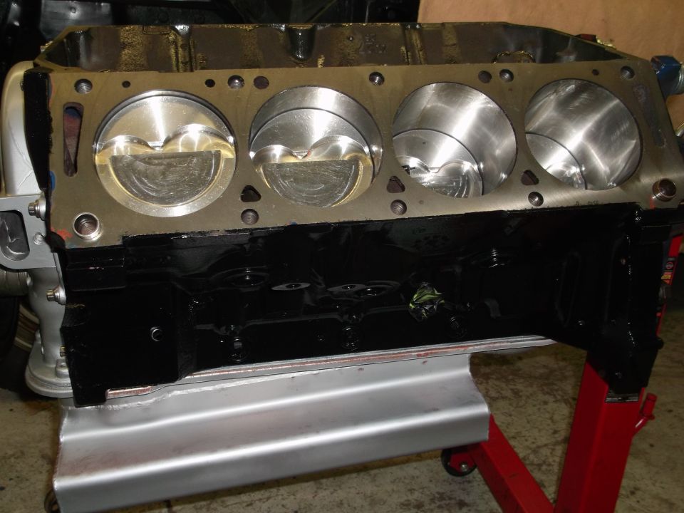 engine block with four pistons visible, sitting on a red engine stand