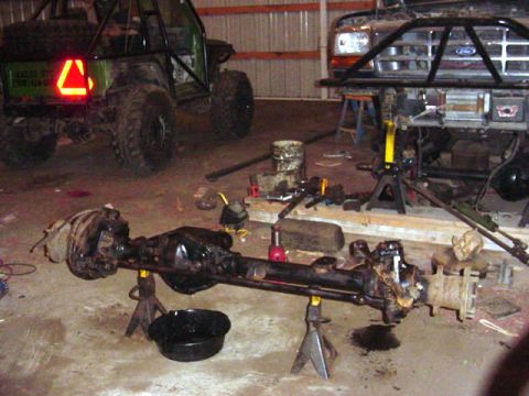 1992 Ford Bronco - Vehicle parts and axles are laid out on the floor of a garage, with two vehicles in the background.