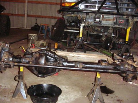 1992 Ford Bronco - Vehicle front axle assembly and chassis are disassembled and supported by jack stands in a garage.