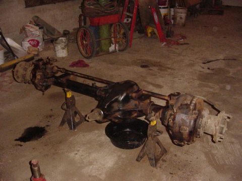 1992 Ford Bronco - A front axle assembly, likely from a truck or SUV, is shown supported by jack stands in a garage setting.