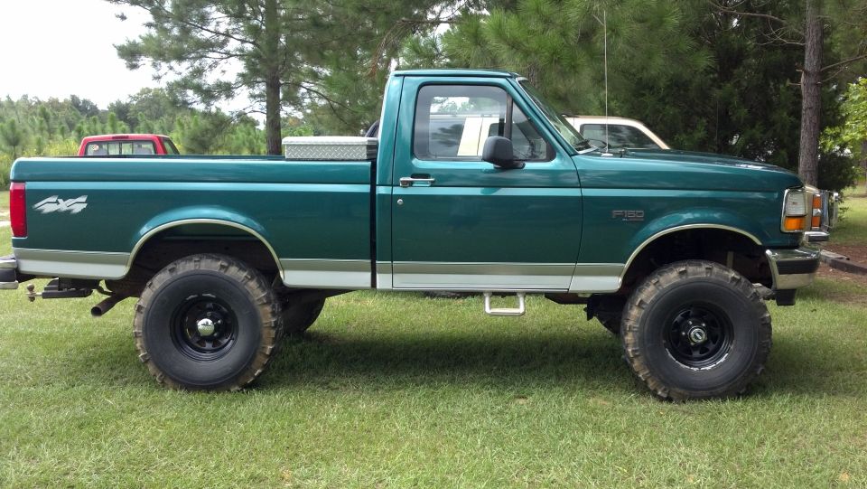 Green 1990s Ford F-150 lifted 4x4 regular cab pickup on grass