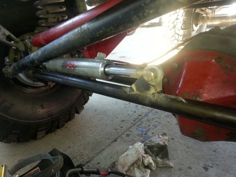 1978 Ford Bronco - Close-up of a steering stabilizer with a checkered logo, part of a vehicle's suspension system.
