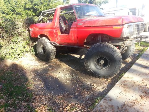 1978 Ford Bronco - This red SUV has been modified for off-road use with large tires and a roll cage.