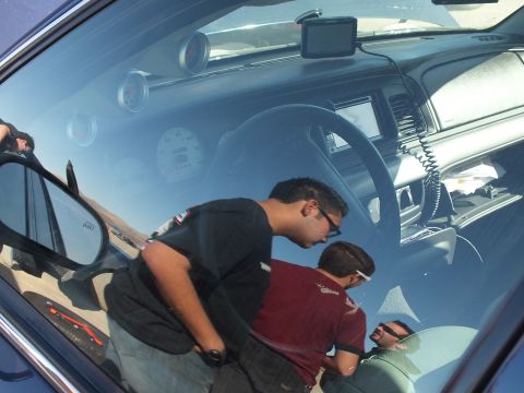 2003 Ford Crown Victoria - Looking through a blue sedan window at the instrument panel and a coiled radio handset.