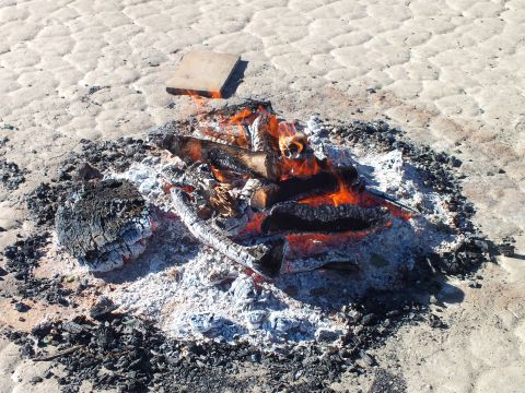 2003 Ford Crown Victoria - Burning logs and red embers ringed by gray ash on the dry desert ground